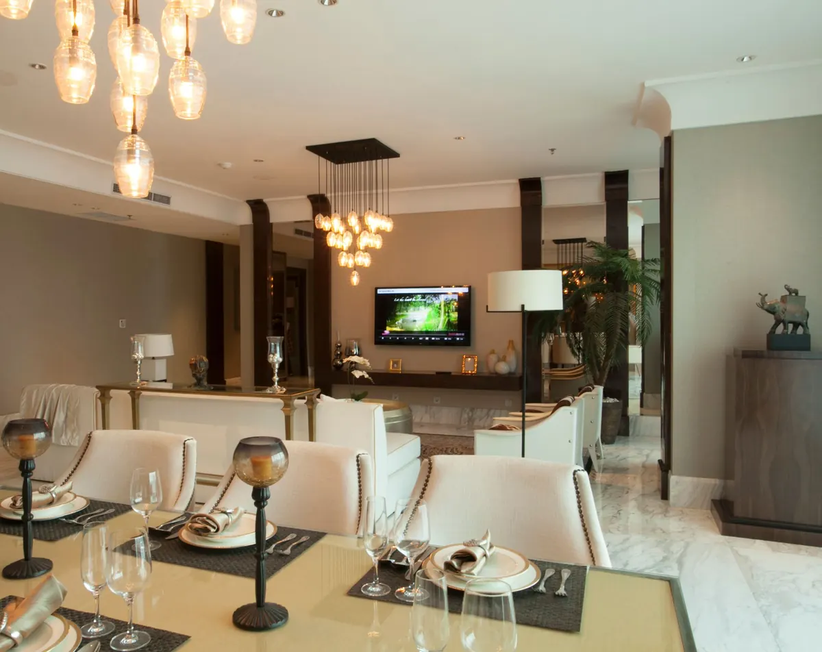 Open dining and living room with glass pendant lights over a set table and a TV on the far wall