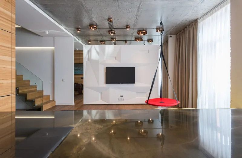 TV mounted flat on a white sculpted feature wall in a modern open room with a wood staircase